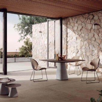 Comfortable Royal Botania Ostrea chair with a black metal frame and beige textile seat, featuring a delicate fan-like backrest and angled legs for outdoor dining