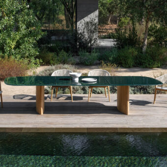 Elegant Royal Botania Regaliz table with dark green glass crafted using a unique melting technique and gracefully curved teak bases
