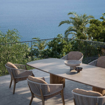 Sophisticated Royal Botania Regaliz table with light gray glass and warm-toned teak bases presenting a textured finish