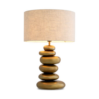 Table by Eichholtz having metal base finished in vintage brass alongside fabric shade showing stacked stone elements