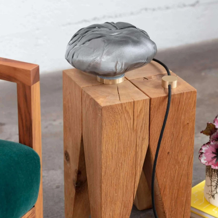 Lamp by Bocci featuring semi translucent metallic grey glass diffuser resting on circular brushed gold toned hardware