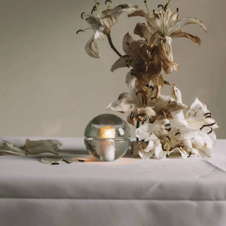 Table lamp by Bocci in clear glass with glossy textured surface and split spherical shade emitting warm internal light