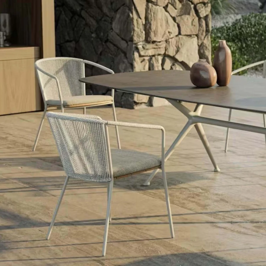 Armchair by Royal Botania Cordiz having matte stainless steel structure solid teak seat cream rope weave plus grey cushion