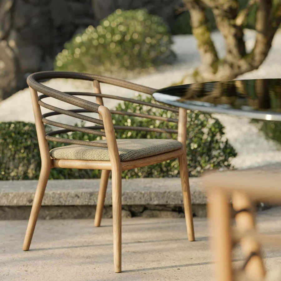 Armchair by Royal Botania featuring a teak wood frame, smooth matte finish, woven rope backrest, and gray green seat cushion