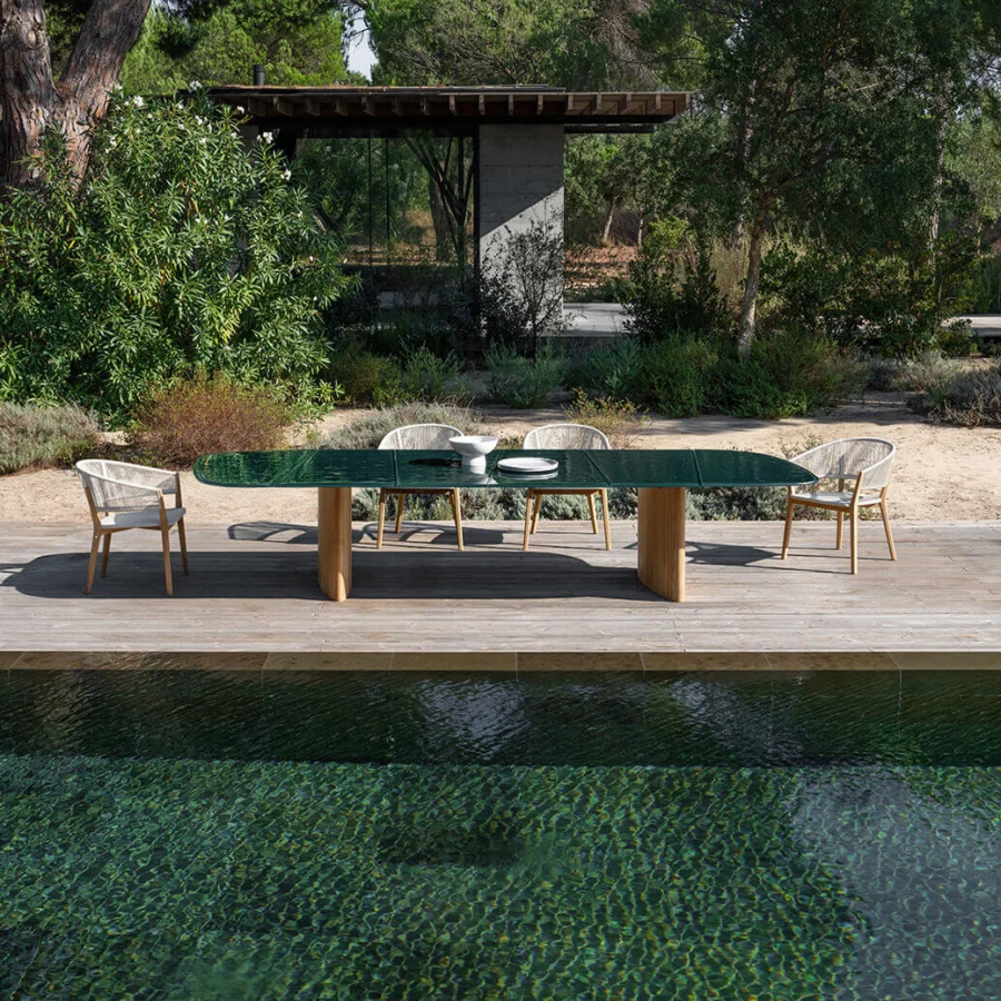 Superior Royal Botania Regaliz table with a textured clear glass top and light-colored teak bases crafted with a satin finish