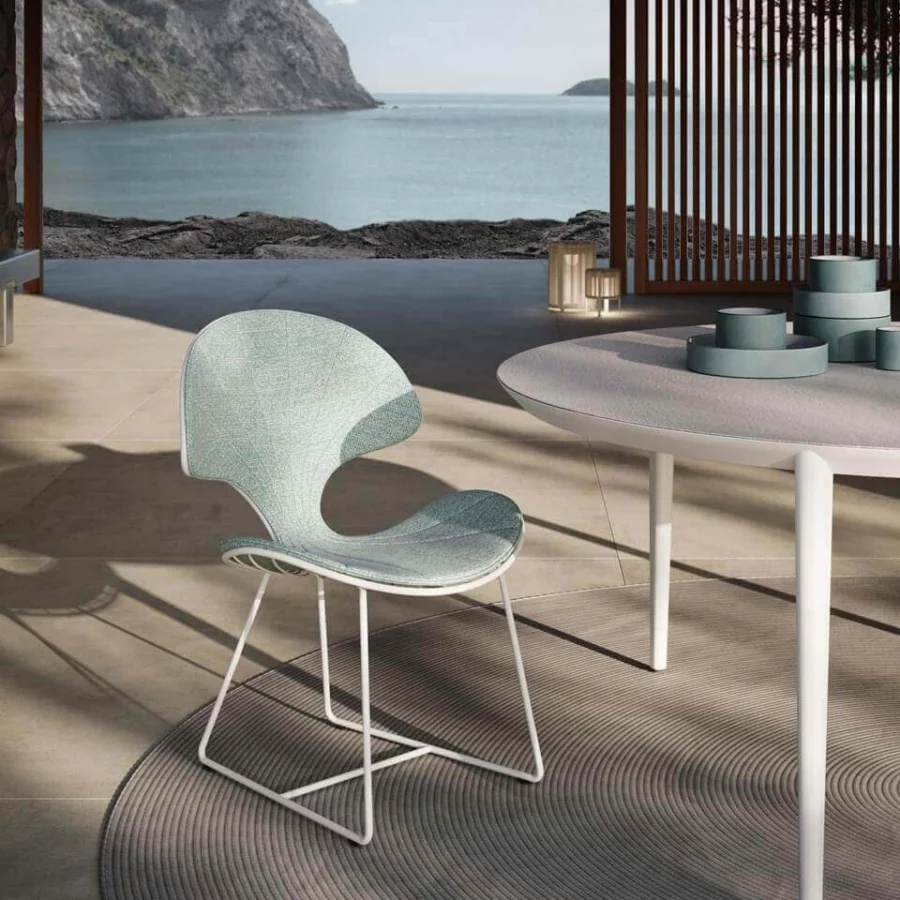 Comfortable Royal Botania Ostrea chair with a light turquoise textile seat and backrest, white metal frame and a darker accent for outdoor dining.