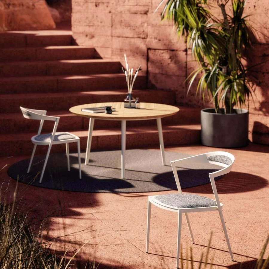 Elegant Royal Botania Styletto table built with tapered legs in coated aluminum and a round teak wood top with a matte finish