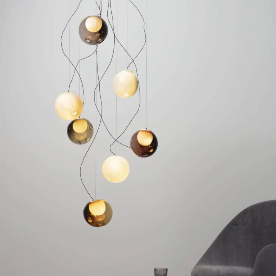 Exceptional Bocci 28 lamp with nine clear glass spheres and milk white interiors suspended by black cables in amber, gold, and smoky gray tones