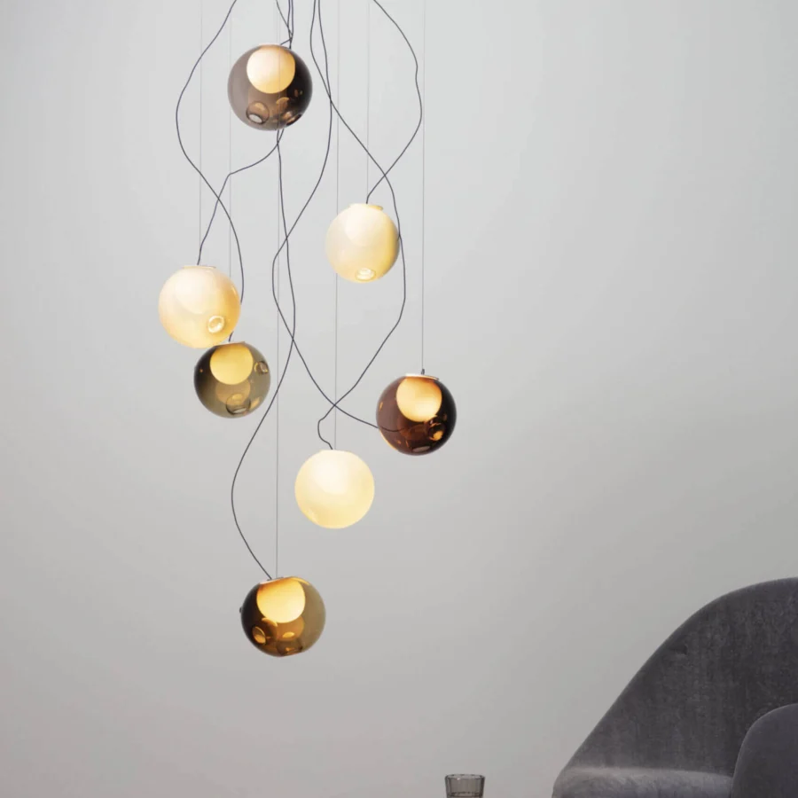 Exceptional Bocci 28 lamp with nine clear glass spheres and milk white interiors suspended by black cables in amber, gold, and smoky gray tones