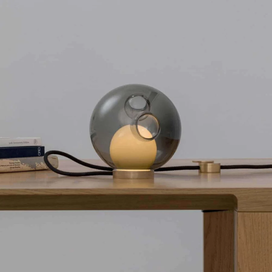 Captivating Bocci 28 table lamp with a smokey gray spherical glass shade and elegant brass base built with a black flexible cord
