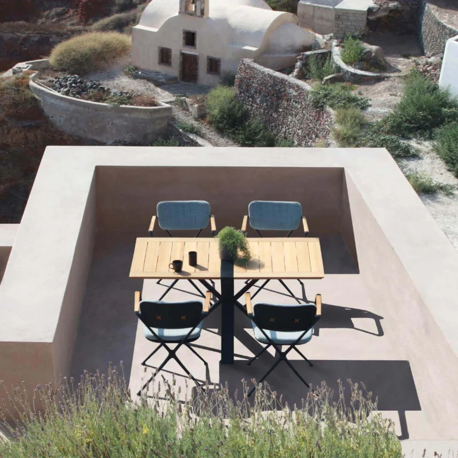 Distinguished Royal Botania Traverse table with light brown teak wood and a dark coated aluminum base built with an X-shaped support