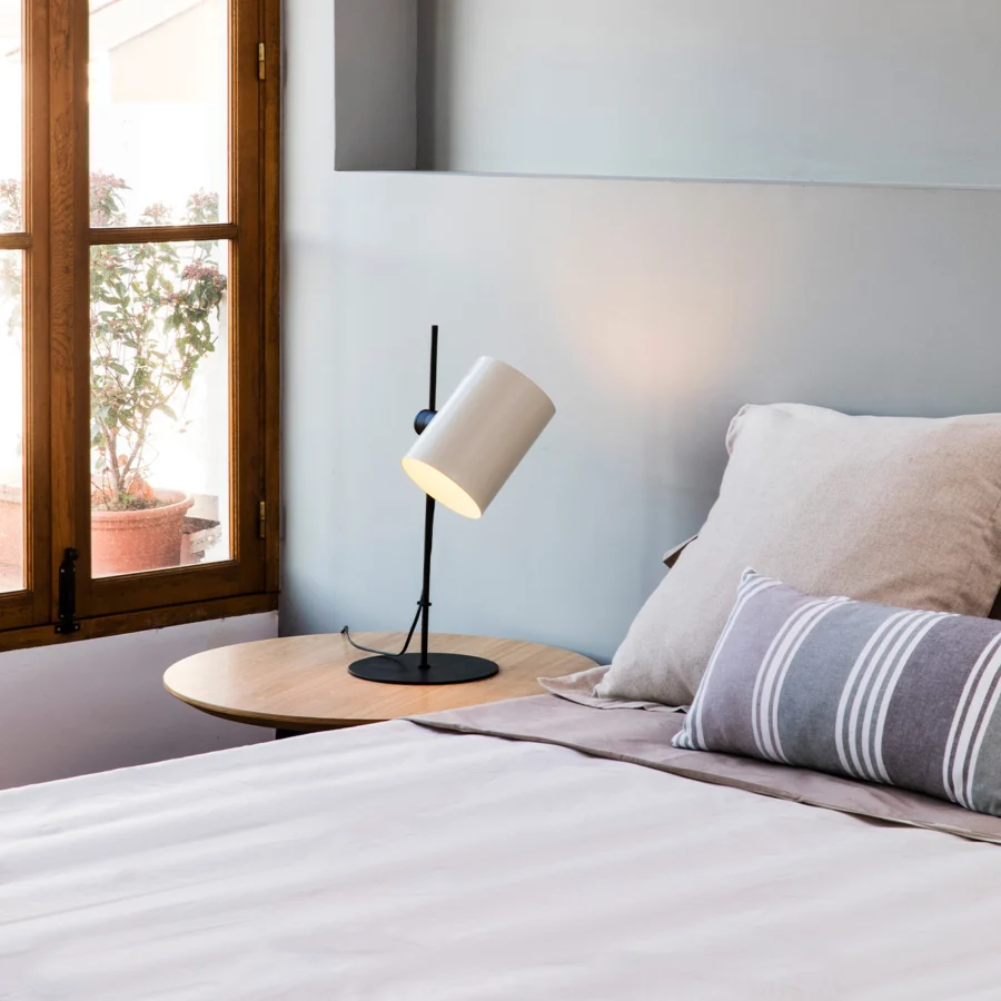 Table lamp by Faro Barcelona in metal with matte black stem base and white cylindrical shade featuring rotation points