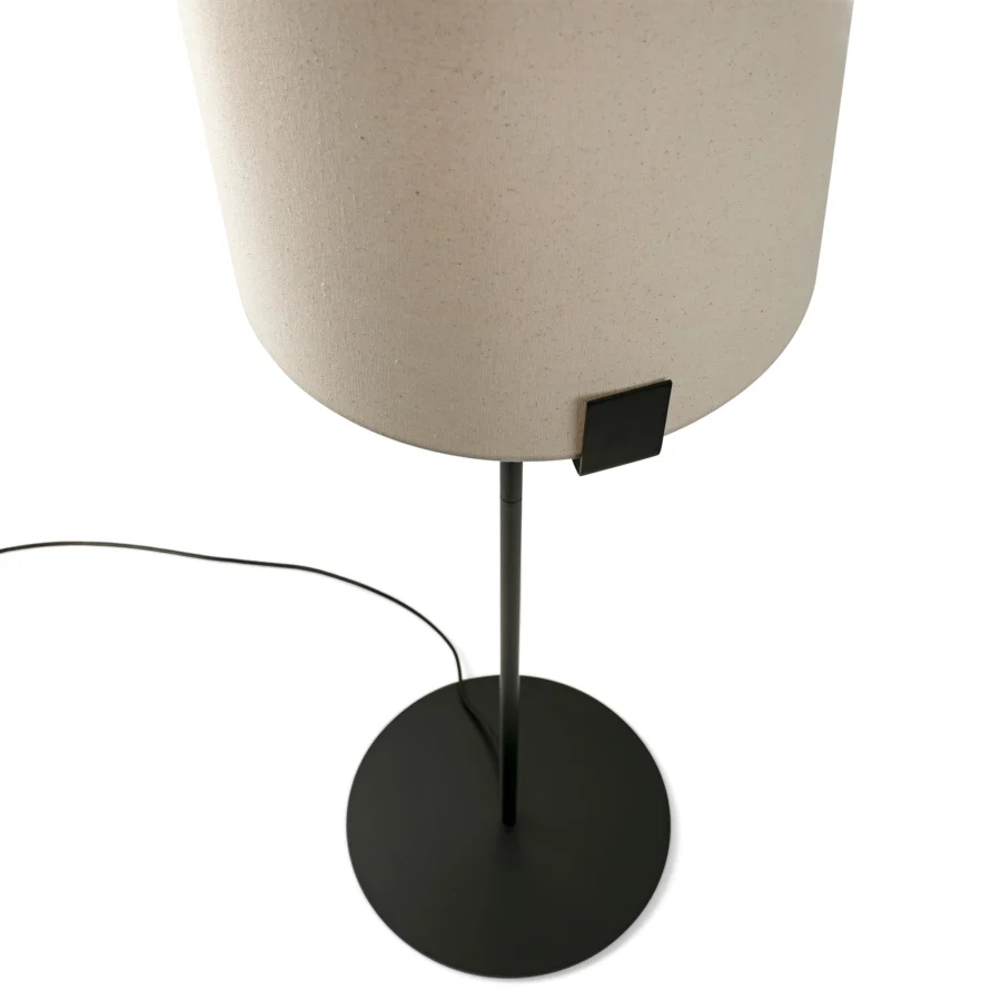 Floor lamp by Faro Barcelona featuring textured off white fabric drum shade, slender metal stem, matte black finish and flat…