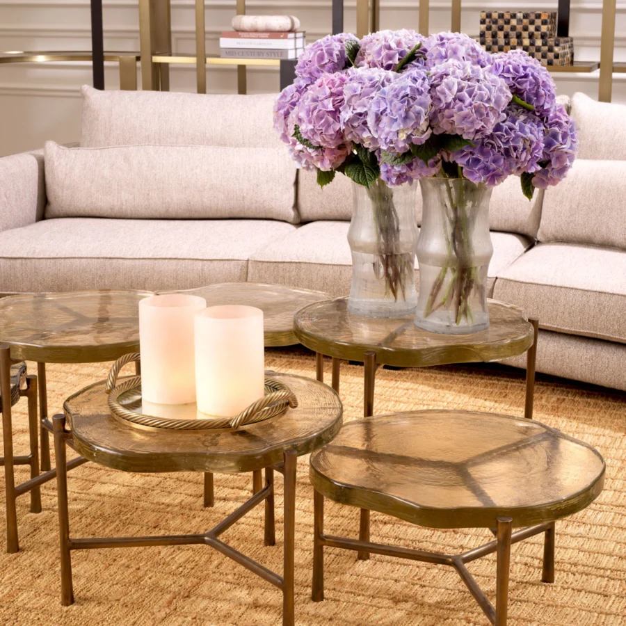 Coffee table set by Eichholtz featuring glass tops and vintage brass finish legs with metal supports